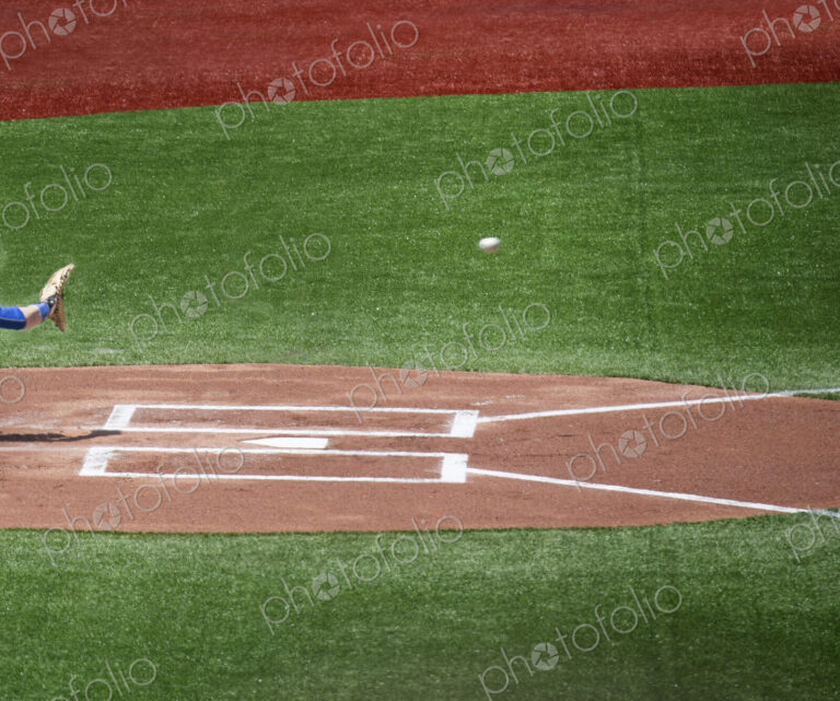 Close up of home plate on baseball field, hand with baseball glove about to catch…