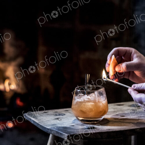 Close up of human hand striking match over glass with alcoholic drink. Close up of human hand striking match over glass with alcoholic drink.