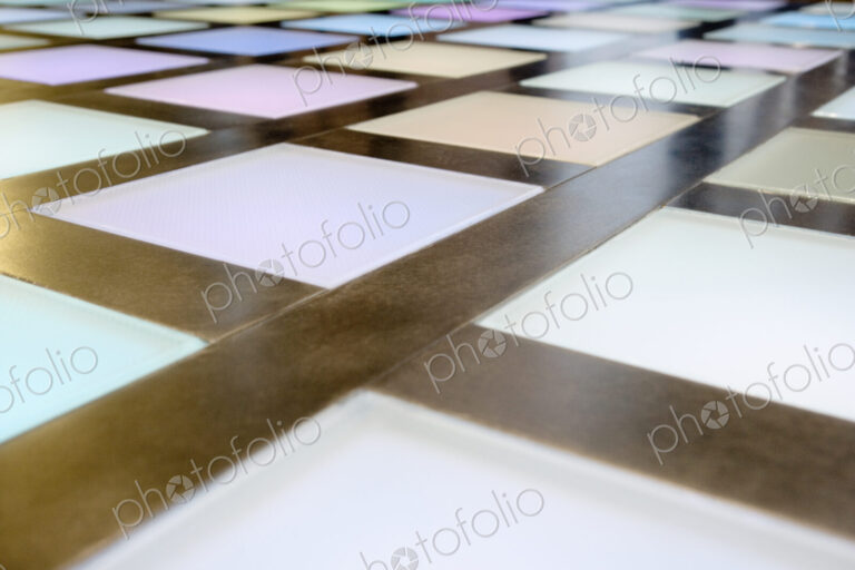 Close-up of illuminated multicoloured tiled dance floor, disco lighting.