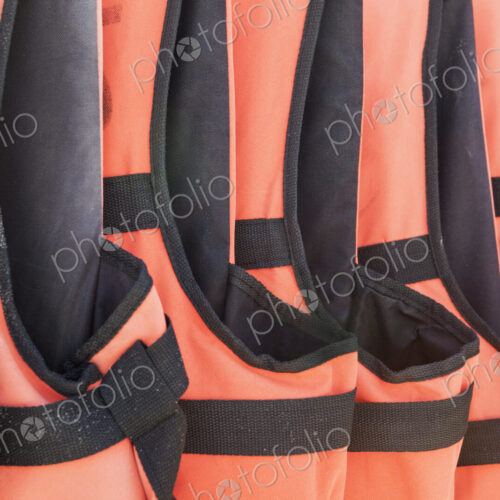 Close-up of orange life jackets in a row Close-up of orange life jackets in a row