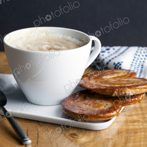 Close up of palmier cookies and cup of coffee