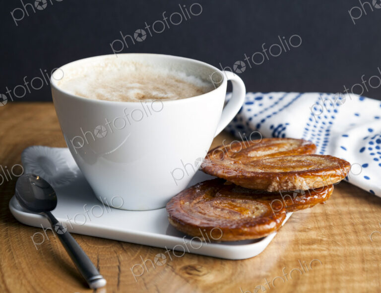 Close up of palmier cookies and cup of coffee