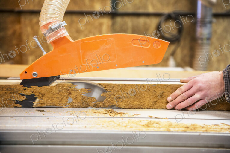 Close up of person cutting piece of recycled wood with a circular saw.