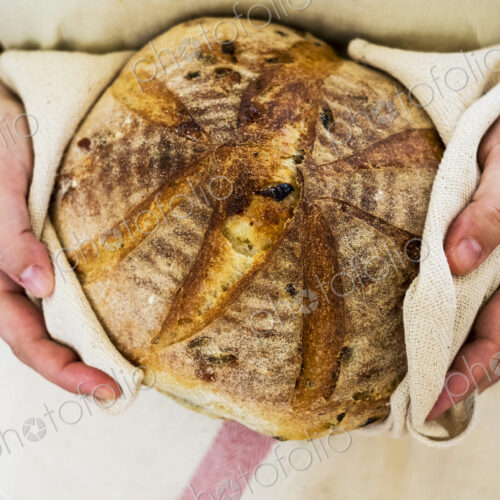 Close up of person holding a freshly baked round loaf of bread. Close up of person holding a freshly baked round loaf of bread.
