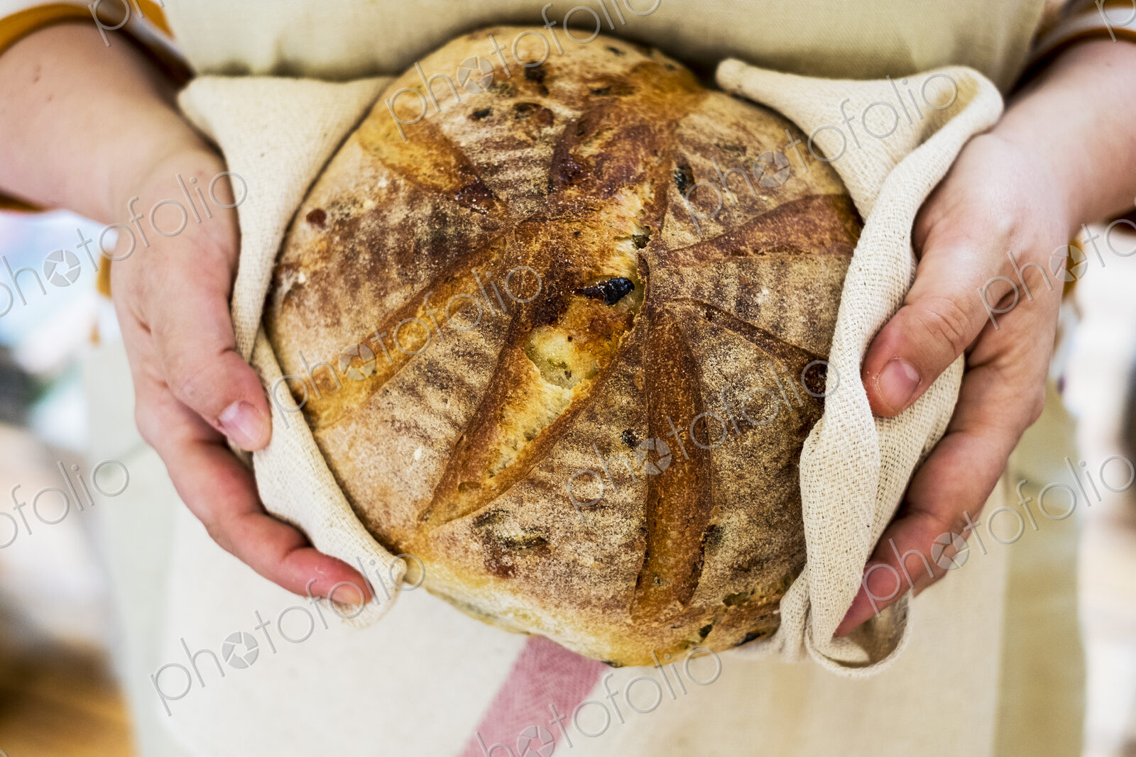 Close up of person holding a freshly baked round loaf of bread.