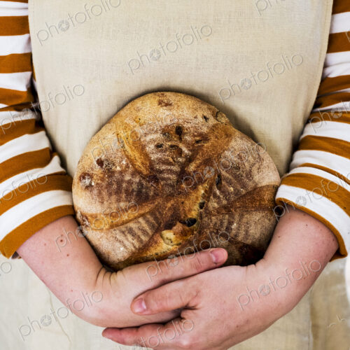 Close up of person holding a freshly baked round loaf of bread. Close up of person holding a freshly baked round loaf of bread.