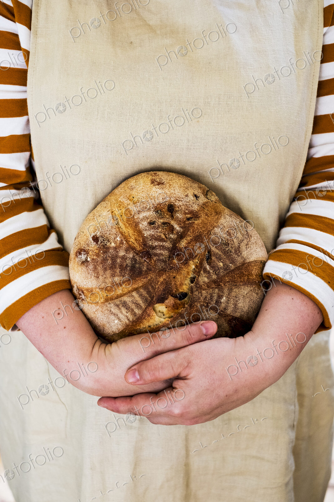 Close up of person holding a freshly baked round loaf of bread.