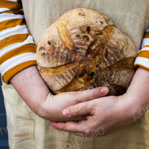 Close up of person holding a freshly baked round loaf of bread. Close up of person holding a freshly baked round loaf of bread.