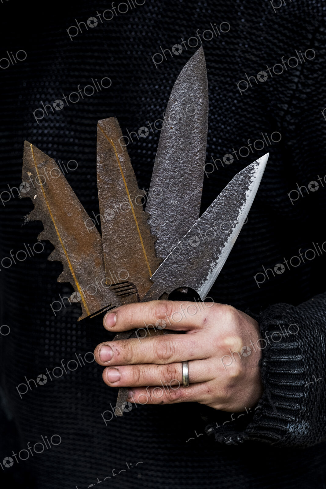 Close up of person holding a selection of partially rusted and serrated knife blades.