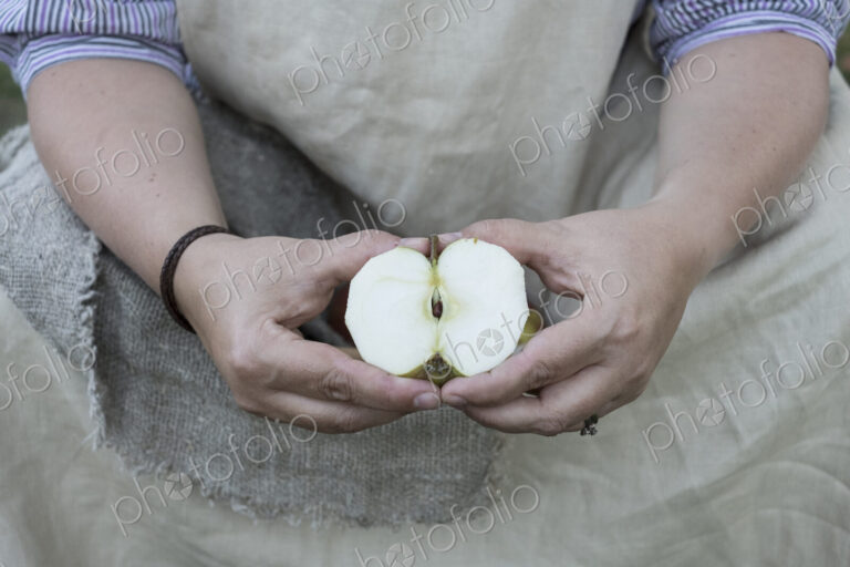 Close up of person holding apple cut in half.