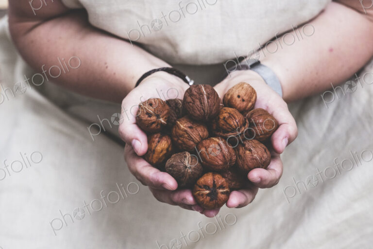 Close up of person holding fresh walnuts.