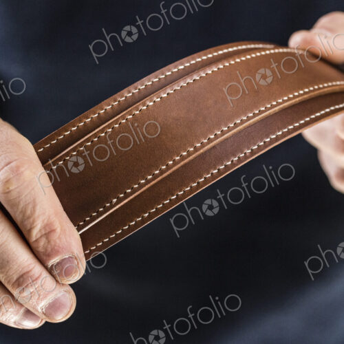 Close up of person holding handmade brown leather camera strap. Close up of person holding handmade brown leather camera strap.