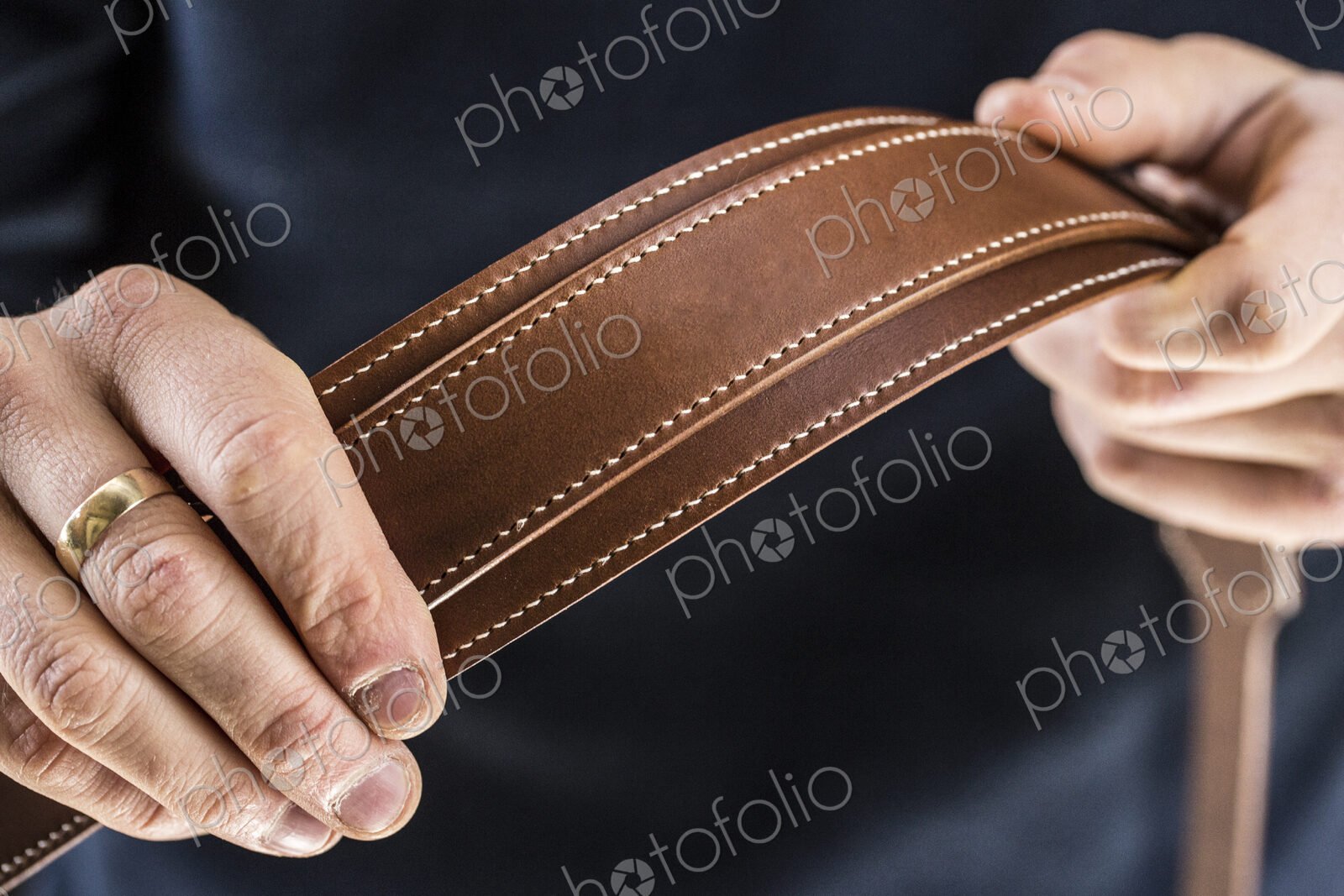 Close up of person holding handmade brown leather camera strap.