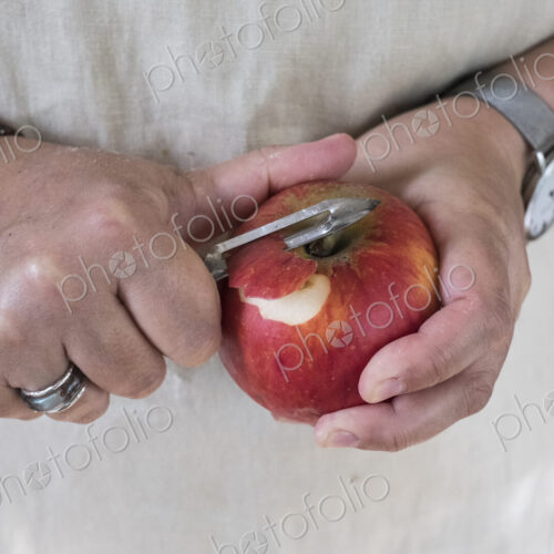 Close up of person peeling a red apple with a double bladed peeler. Close up of person peeling a red apple with a double bladed peeler.