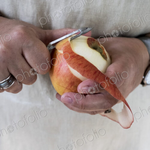 Close up of person peeling a red apple with a double bladed peeler. Close up of person peeling a red apple with a double bladed peeler.