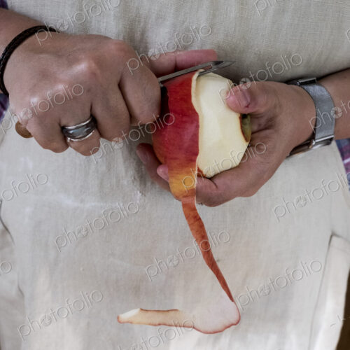 Close up of person peeling a red apple with a double bladed peeler. Close up of person peeling a red apple with a double bladed peeler.