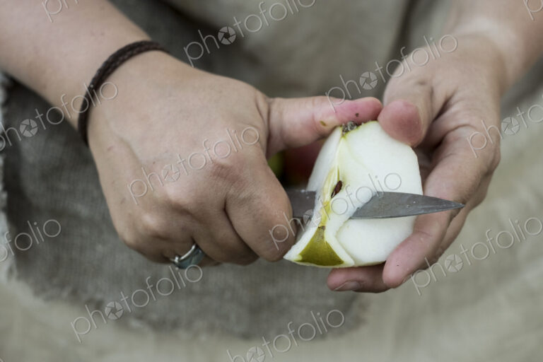 Close up of person peeling apple with knife.
