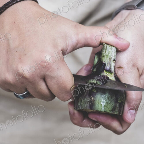 Close up of person peeling fresh artichoke with kitchen knife. Close up of person peeling fresh artichoke with kitchen knife.