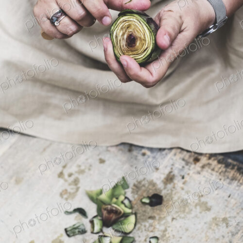 Close up of person peeling fresh artichoke with kitchen knife. Close up of person peeling fresh artichoke with kitchen knife.
