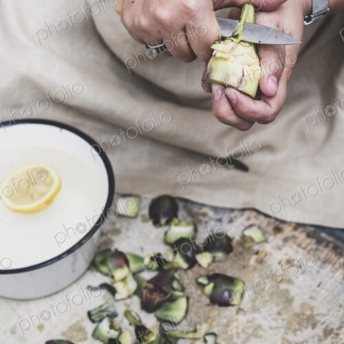 Close up of person peeling fresh artichoke with kitchen knife. Close up of person peeling fresh artichoke with kitchen knife.