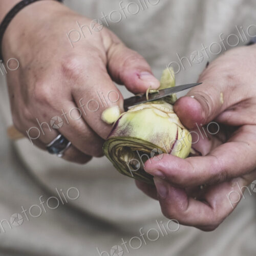 Close up of person peeling fresh artichoke with kitchen knife. Close up of person peeling fresh artichoke with kitchen knife.