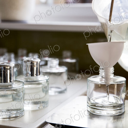Close up of person pouring liquid for scent diffuser into glass bottle.