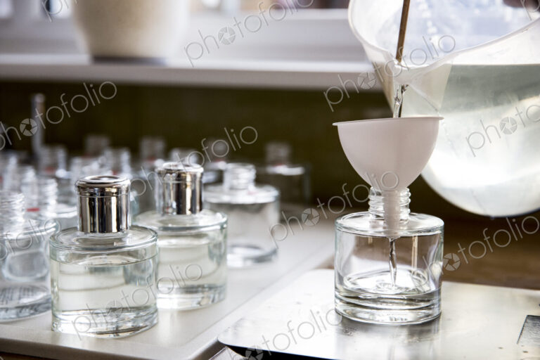 Close up of person pouring liquid for scent diffuser into glass bottle.