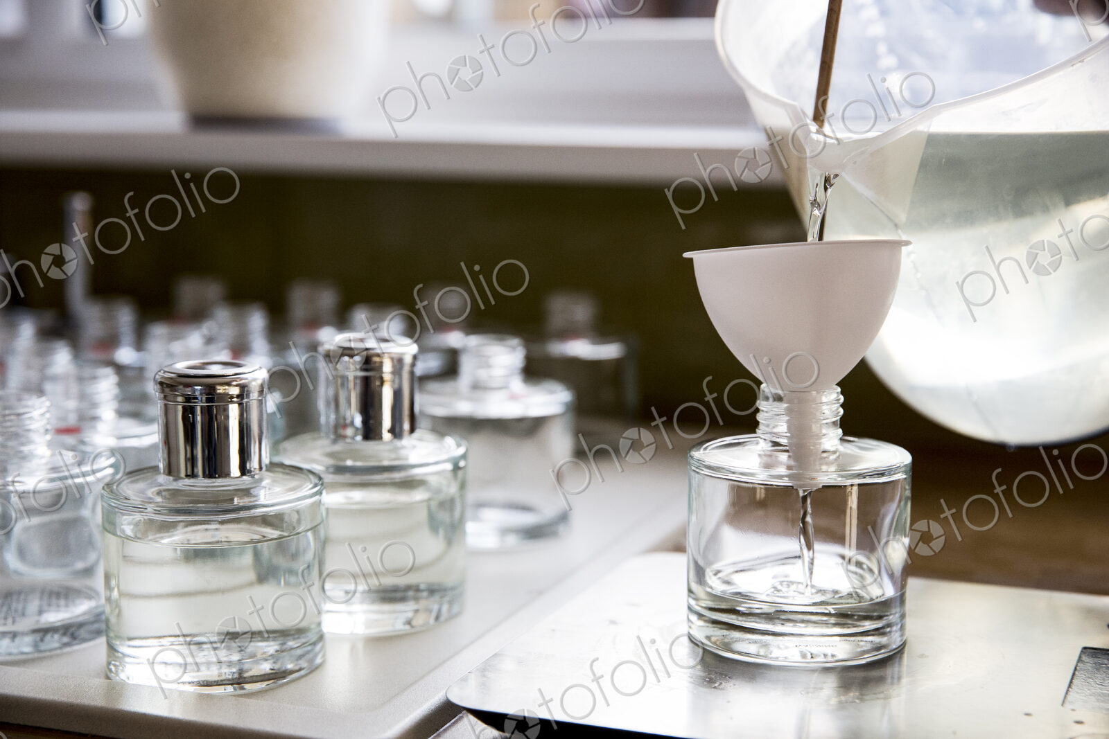 Close up of person pouring liquid for scent diffuser into glass bottle.