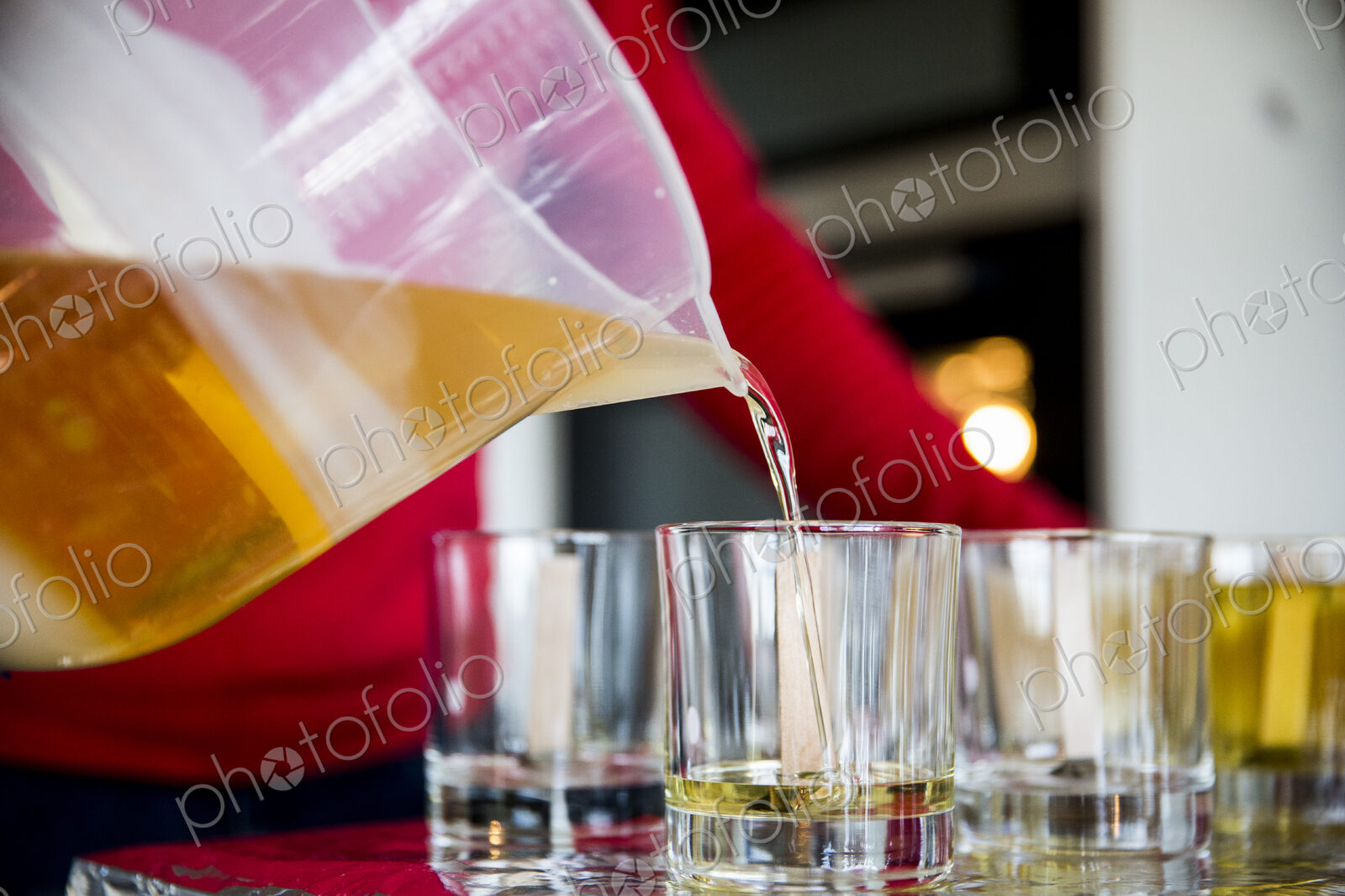 Close up of person pouring liquid wax for handmade candles into glass jars.