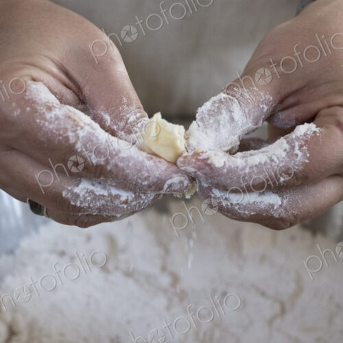 Close up of person rubbing in butter and flour for a crumble between her finger tips.