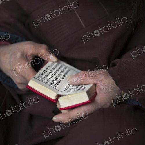 Close up of person wearing purple robe, holding prayer book in hands. Close up of person wearing purple robe, holding prayer book in hands.