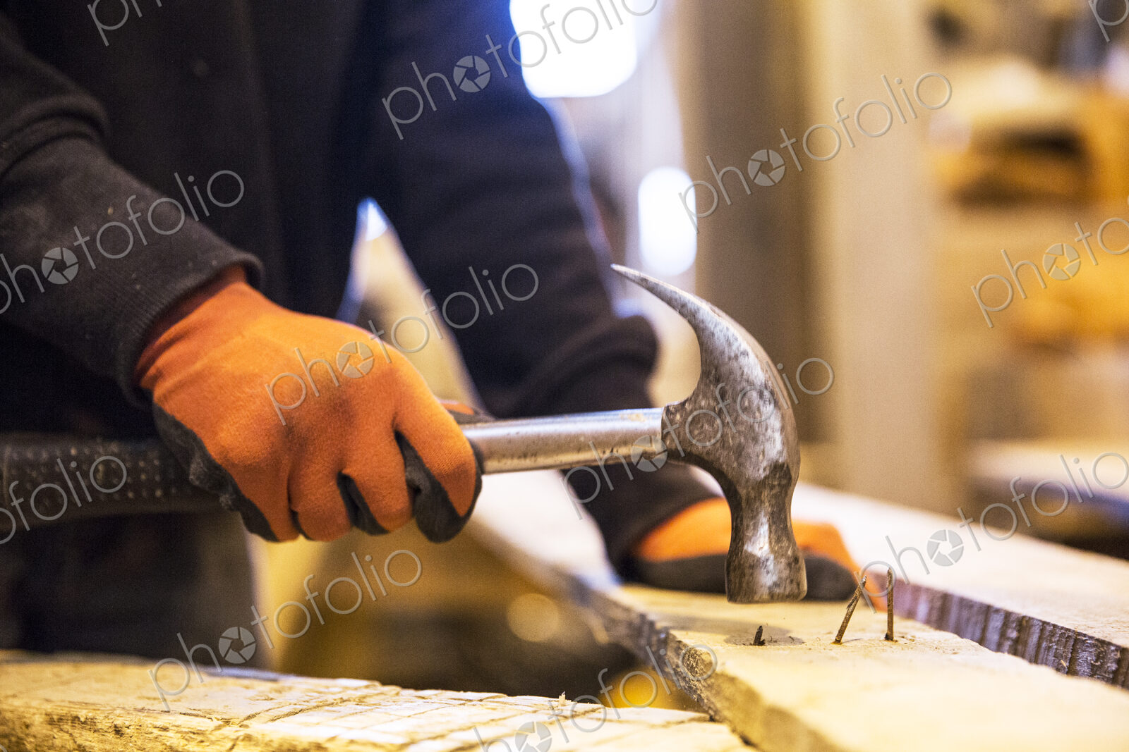 Close up of person wearing work gloves holding, hammer, removing rusty nails from…