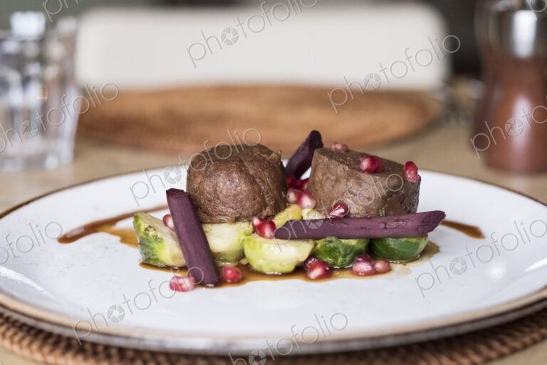 Close up of plate of food, beef with Brussels Sprouts and beetroot and a garnish of…