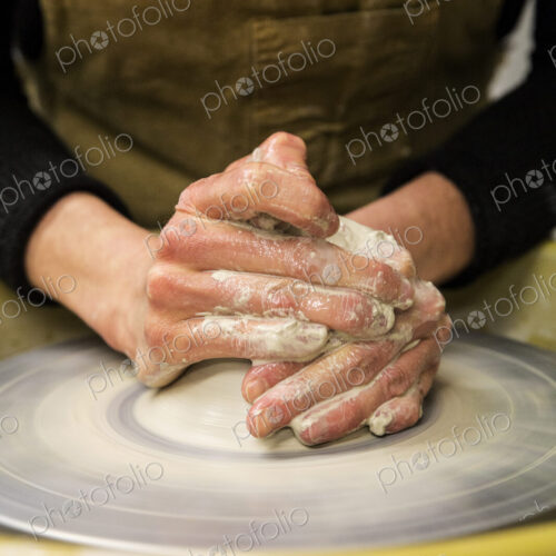 Close up of potter wearing apron working on pottery wheel, shaping clay. Close up of potter wearing apron working on pottery wheel, shaping clay.