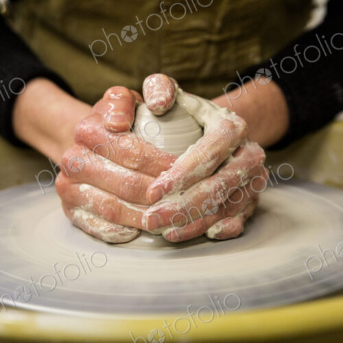 Close up of potter wearing apron working on pottery wheel, shaping clay. Close up of potter wearing apron working on pottery wheel, shaping clay.