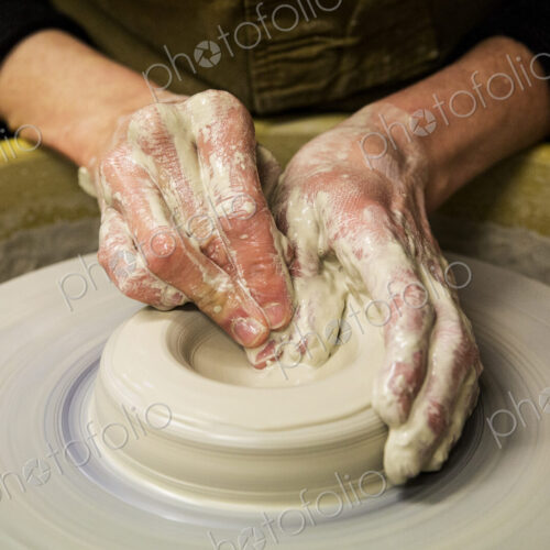 Close up of potter wearing apron working on pottery wheel, shaping clay vase. Close up of potter wearing apron working on pottery wheel, shaping clay vase.