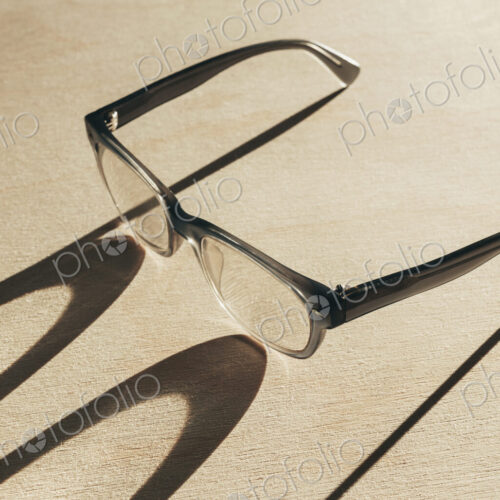 Close up of reading glasses casting long shadow Close up of reading glasses casting long shadow