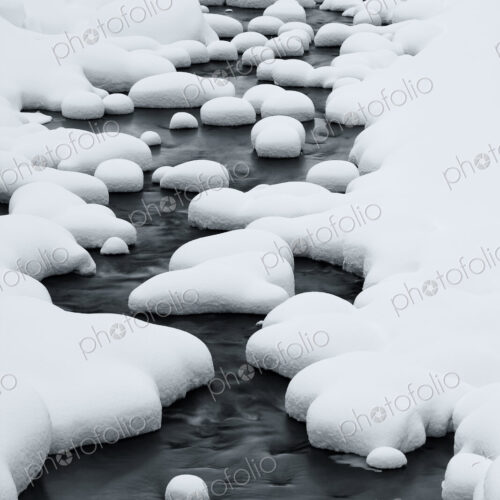 Close up of riverbed with snow-covered rocks in winter. Close up of riverbed with snow-covered rocks in winter.