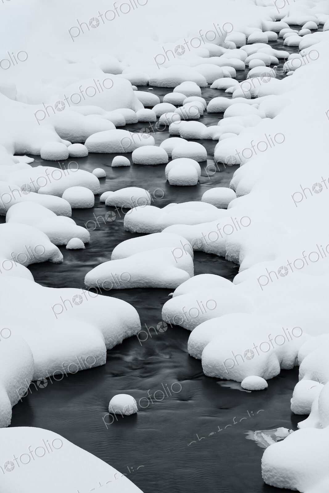 Close up of riverbed with snow-covered rocks in winter.