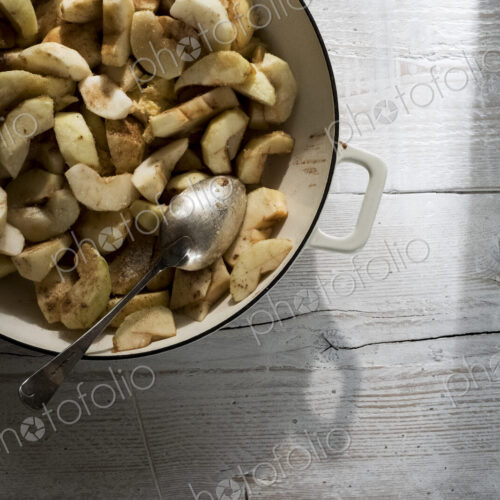 Close up of round baking tin with apple slices and blackberries.