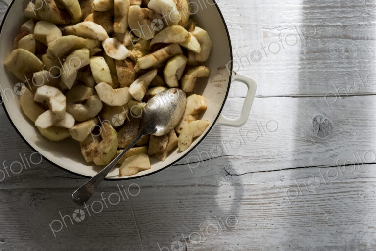 Close up of round baking tin with apple slices and blackberries.