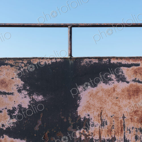 Close up of rusty black wall with railing. Close up of rusty black wall with railing.
