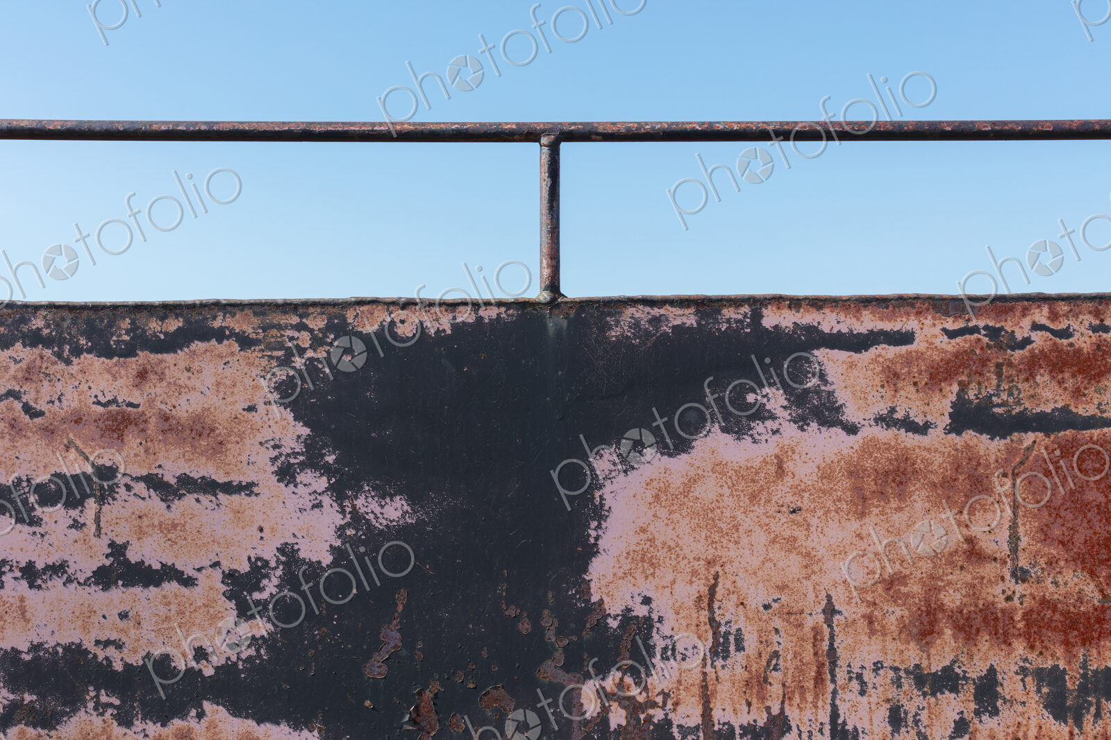 Close up of rusty black wall with railing.