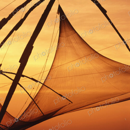Close up of sail of traditional boat at dusk, two fisherman in a fishing boat.