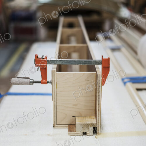 Close up of small bar clamps being used in a woodworking factory.