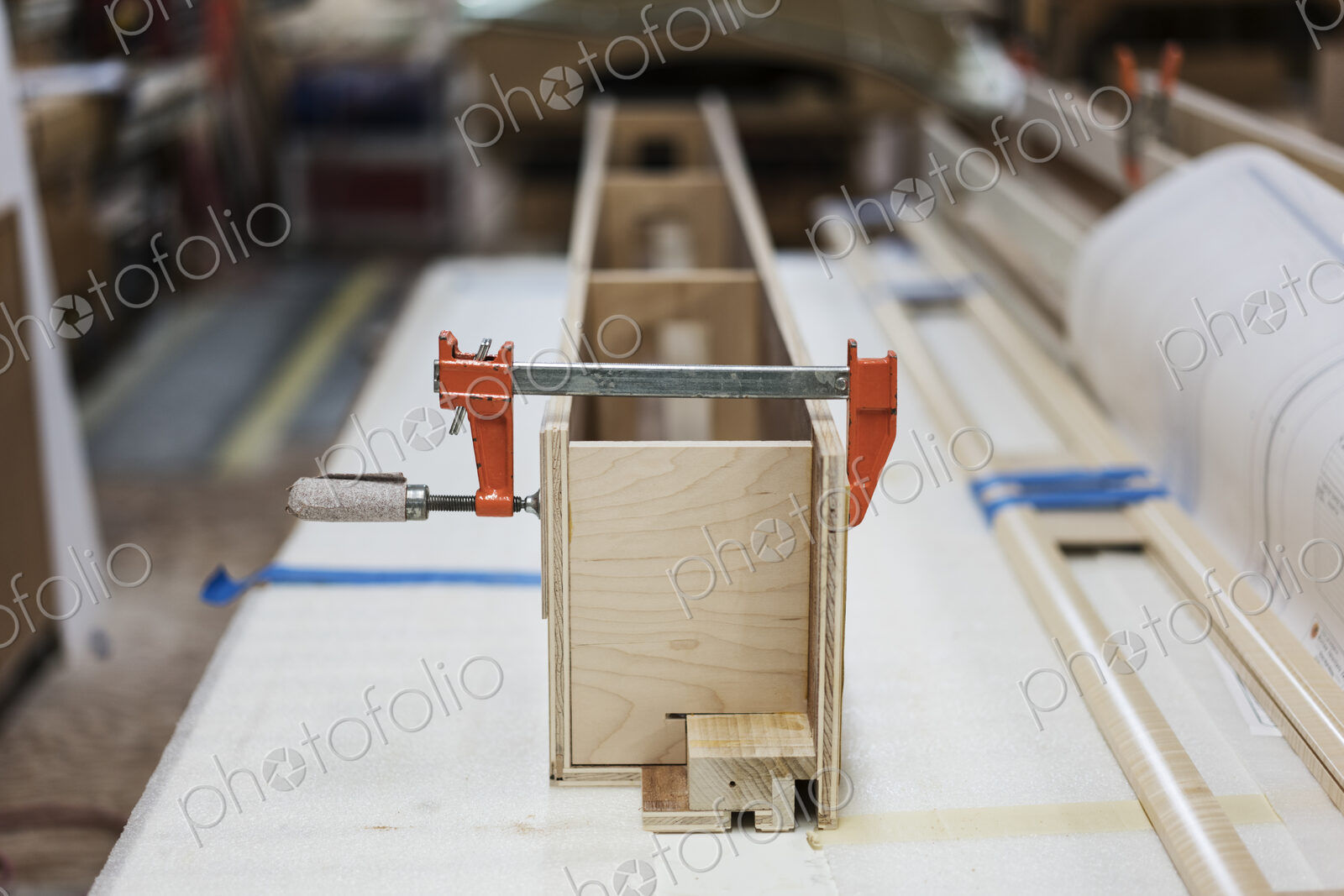 Close up of small bar clamps being used in a woodworking factory.