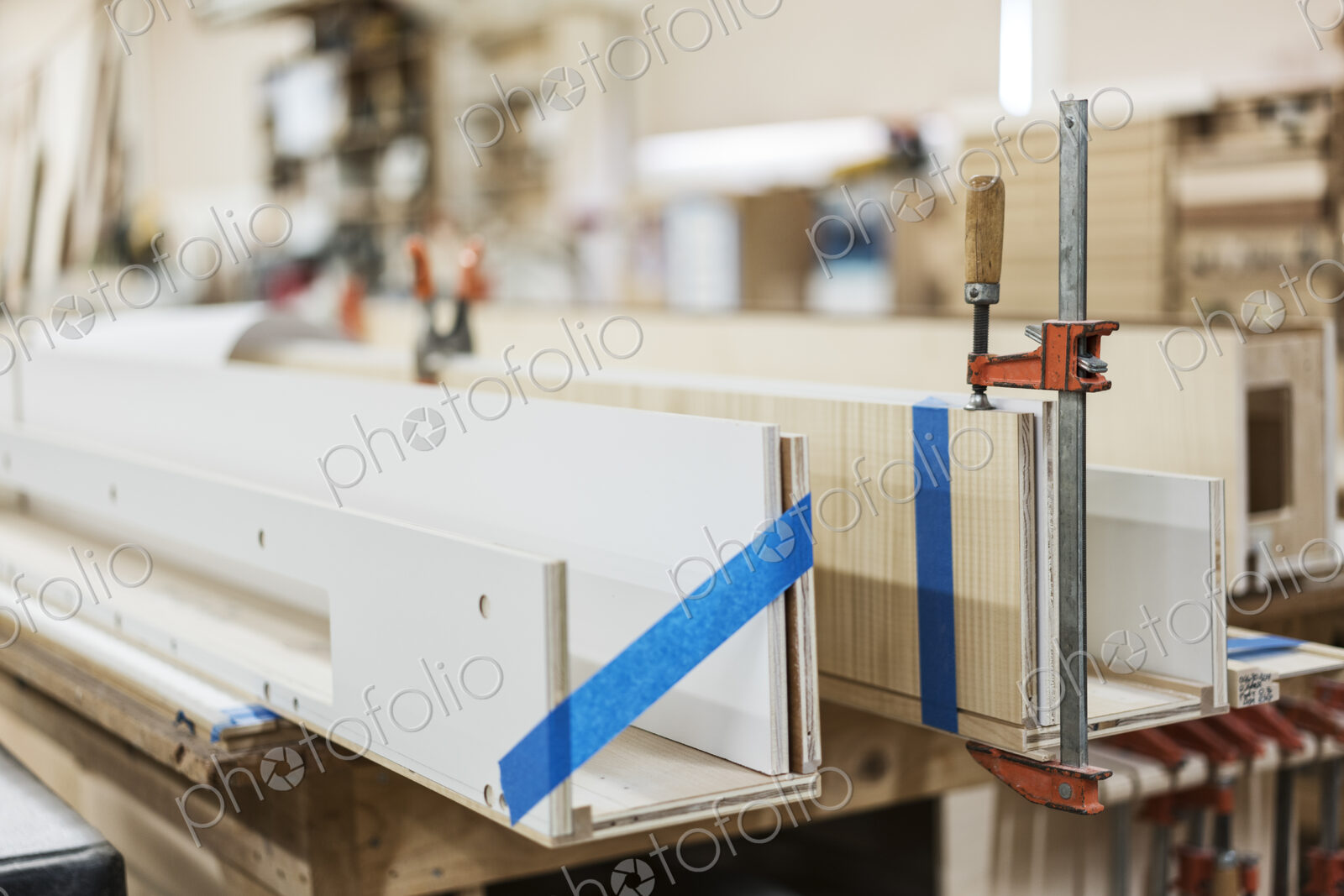 Close up of small bar clamps being used in a woodworking factory.