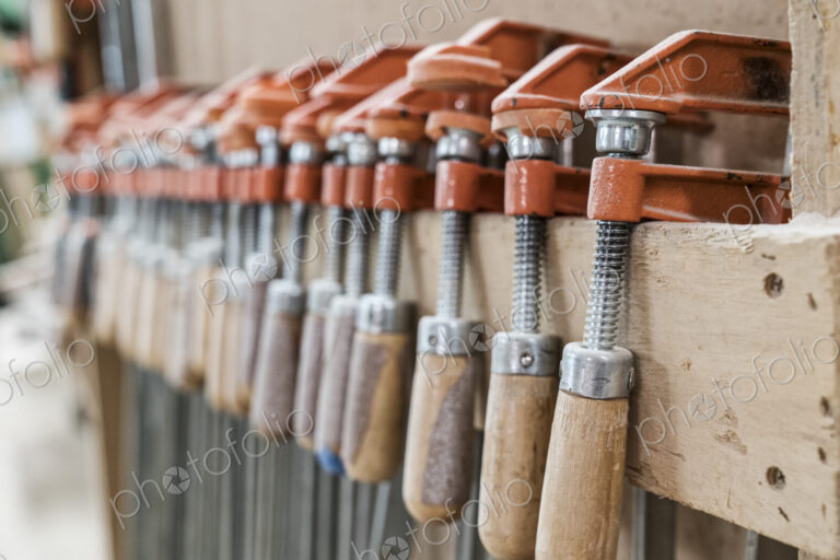 Close up of small bar clamps being used in a woodworking factory.