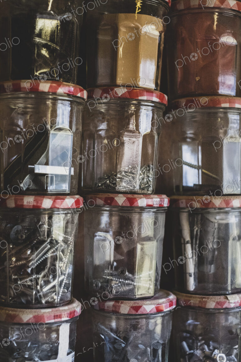 Close up of stack of jam jars containing selection of nail and screws.