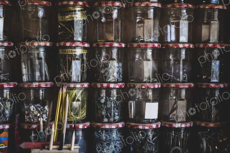 Close up of stack of jam jars containing selection of nail and screws.